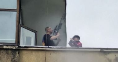Stire din Eveniment : Scene șocante, surprinse pe terasa unui bloc. Un bărbat a ieșit cu o armă cu lunetă, alături de un minor